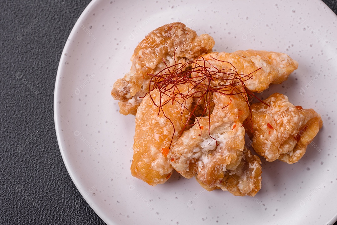 Deliciosos suculentos pedaços de frango grelhado em molho agridoce com sal e especiarias num prato cerâmico