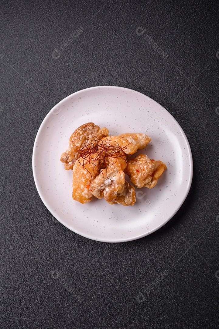 Deliciosos suculentos pedaços de frango grelhado em molho agridoce com sal e especiarias num prato cerâmico