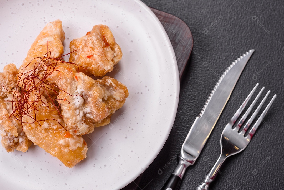 Deliciosos suculentos pedaços de frango grelhado em molho agridoce com sal e especiarias num prato cerâmico