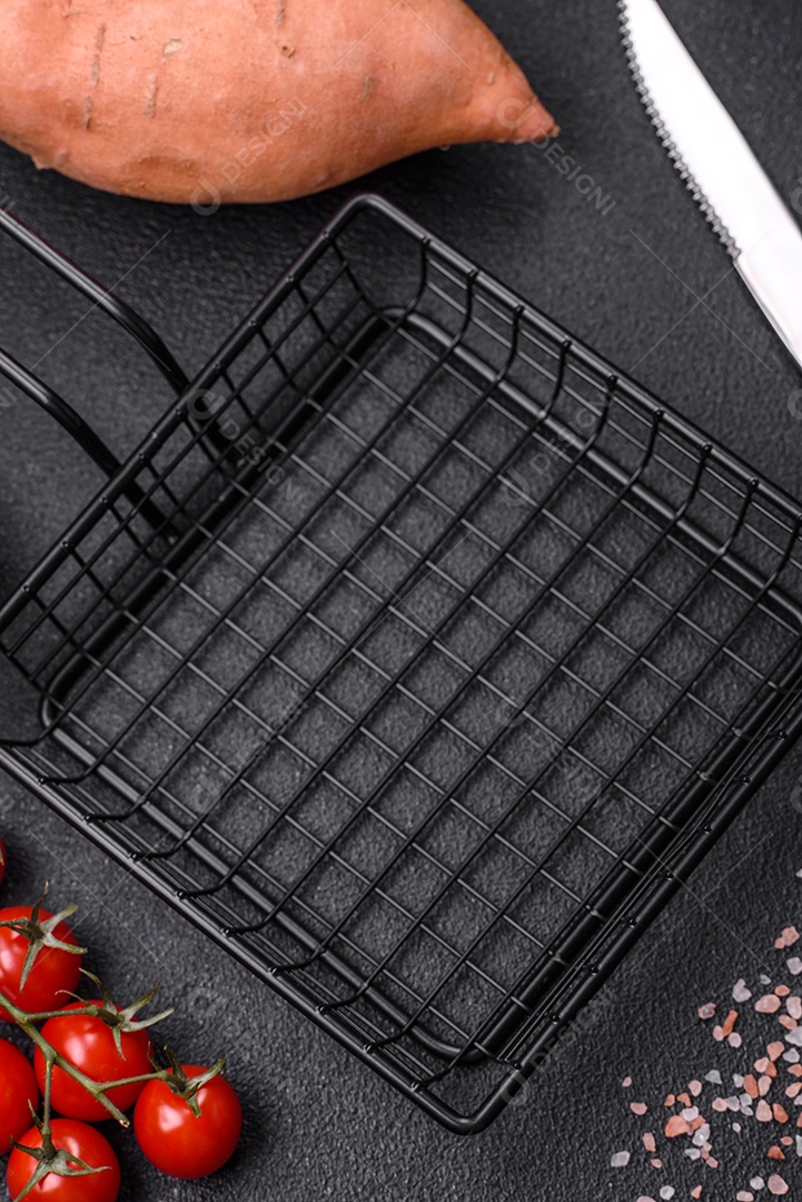 Grandes tubérculos frescos de batata-doce rosa com tomates e especiarias em um fundo escuro. Cozinhando uma refeição vegetariana saudável