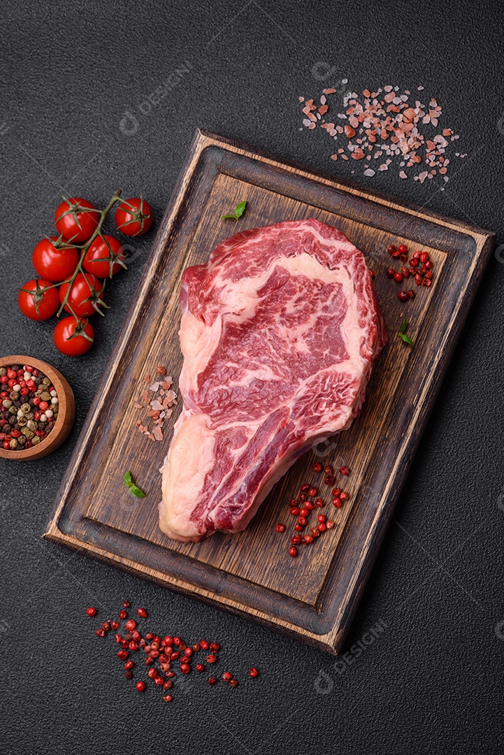 Bife fresco e suculento de carne crua com sal e especiarias sobre um fundo escuro de concreto