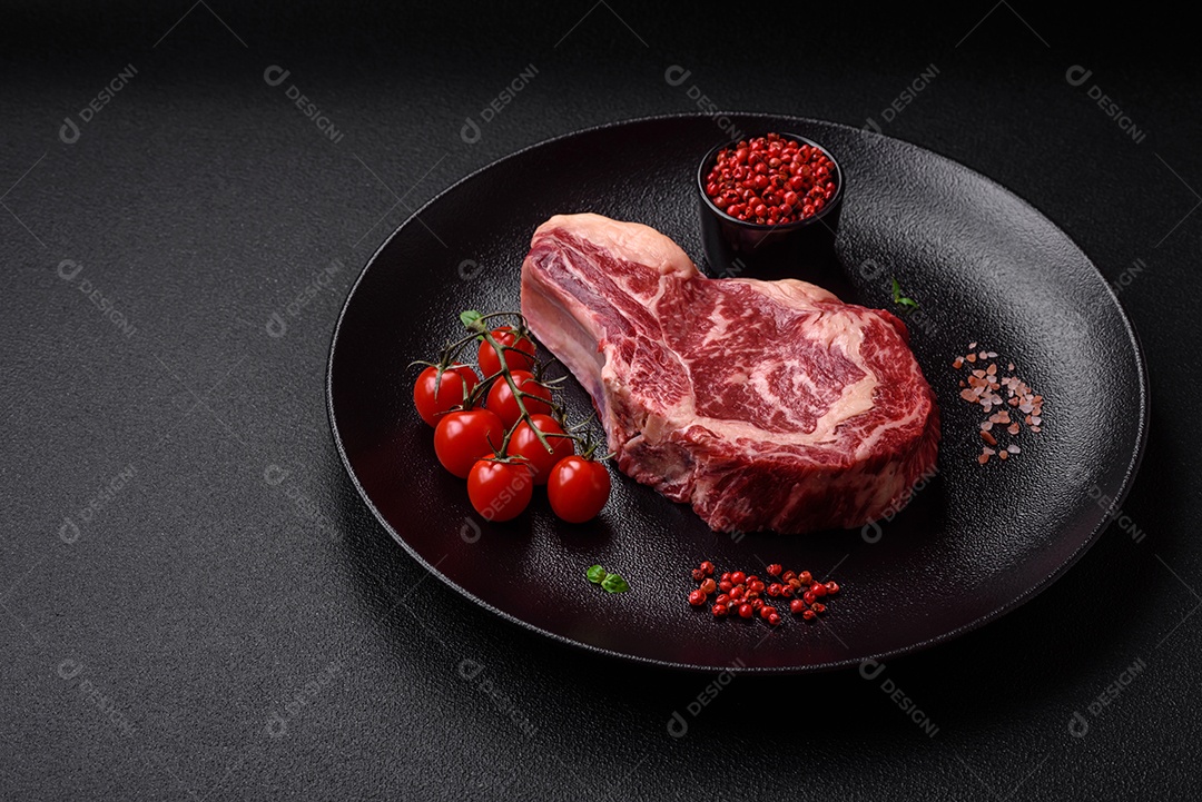 Bife fresco e suculento de carne crua com sal e especiarias sobre um fundo escuro de concreto
