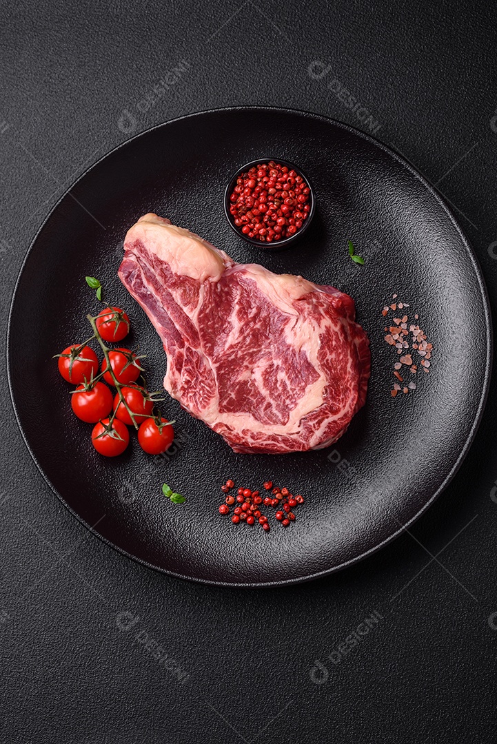 Bife fresco e suculento de carne crua com sal e especiarias sobre um fundo escuro de concreto