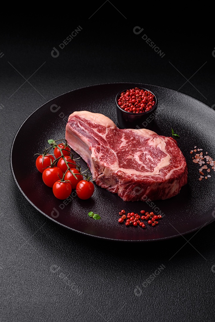 Bife fresco e suculento de carne crua com sal e especiarias sobre um fundo escuro de concreto