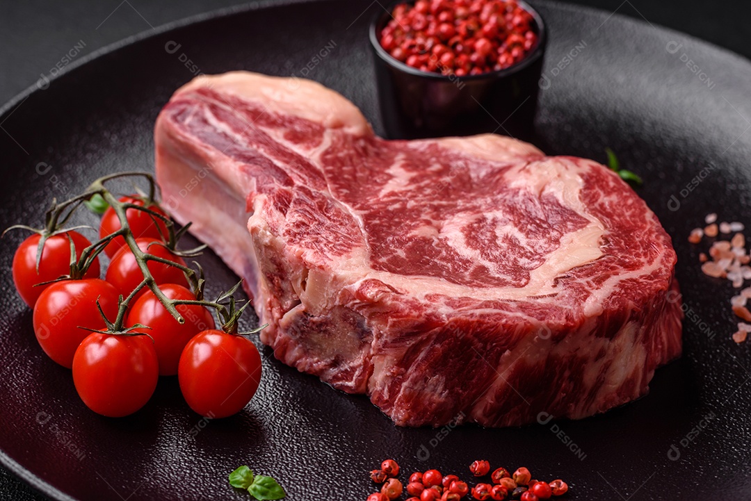 Bife fresco e suculento de carne crua com sal e especiarias sobre um fundo escuro de concreto