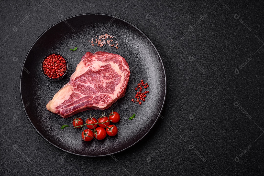 Bife fresco e suculento de carne crua com sal e especiarias sobre um fundo escuro de concreto