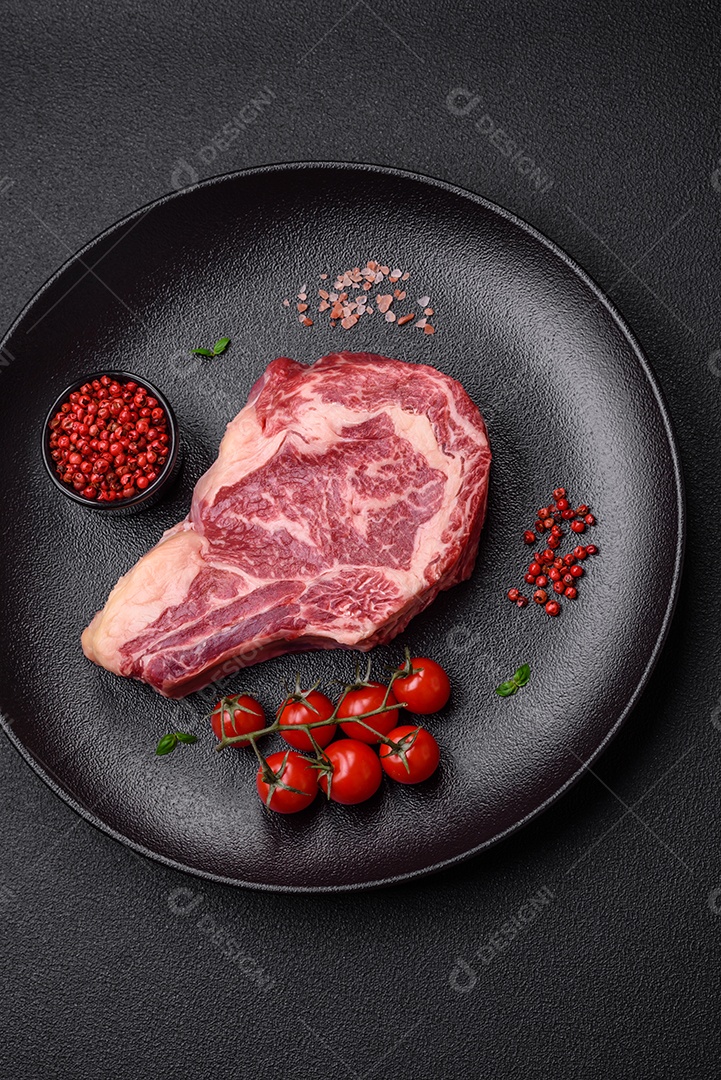 Bife fresco e suculento de carne crua com sal e especiarias sobre um fundo escuro de concreto