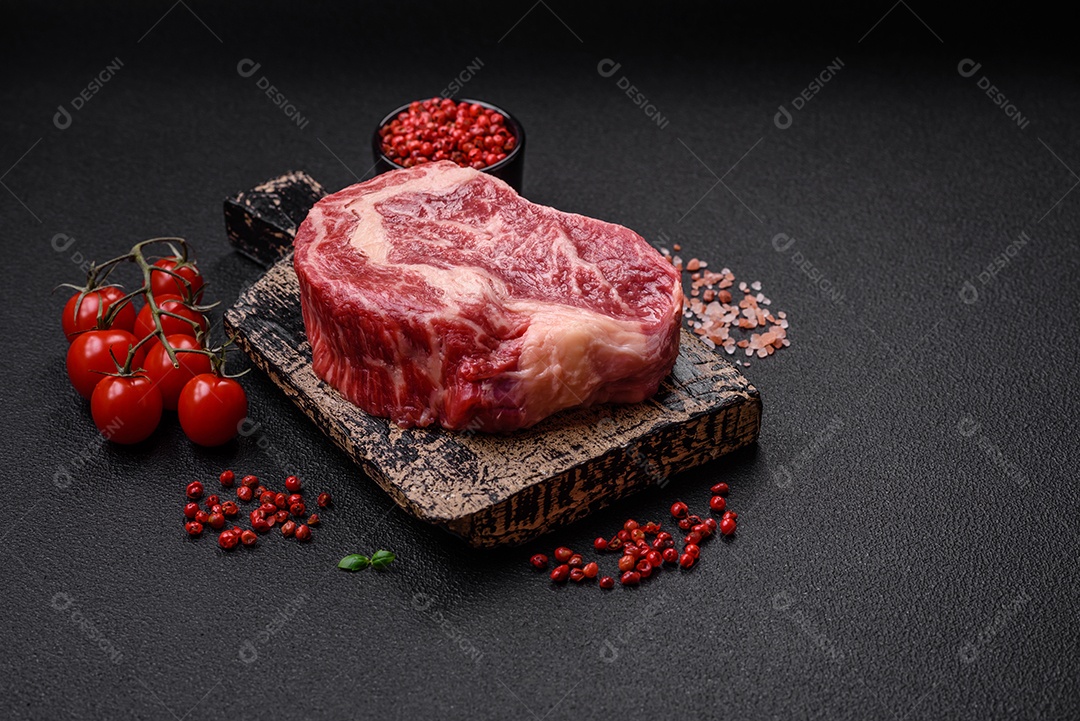 Bife fresco e suculento de carne crua com sal e especiarias sobre um fundo escuro de concreto