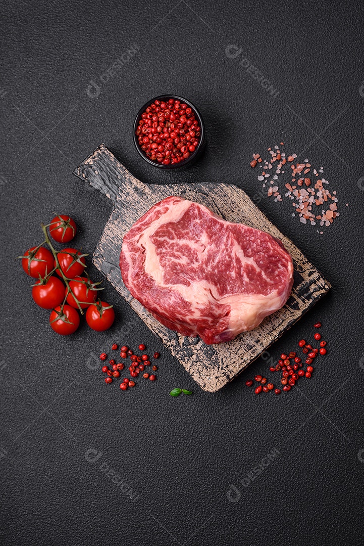 Bife fresco e suculento de carne crua com sal e especiarias sobre um fundo escuro de concreto