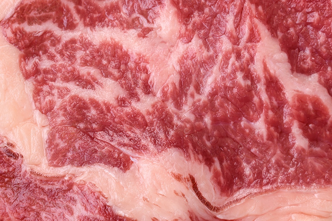 Bife fresco e suculento de carne crua com sal e especiarias sobre um fundo escuro de concreto