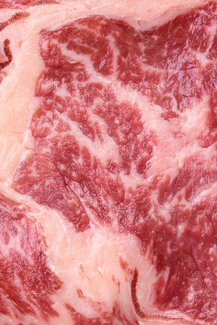 Bife fresco e suculento de carne crua com sal e especiarias sobre um fundo escuro de concreto