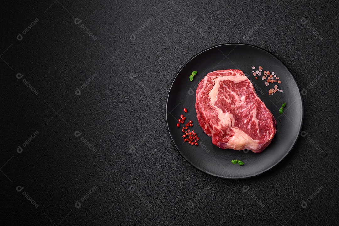 Bife fresco e suculento de carne crua com sal e especiarias sobre um fundo escuro de concreto