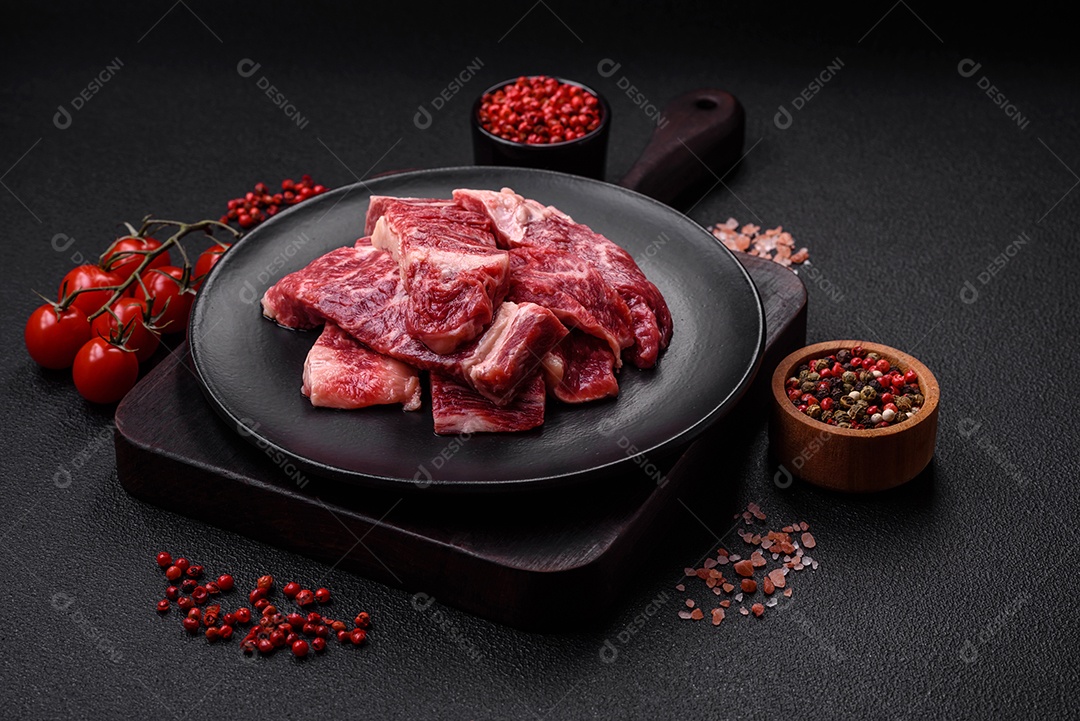 Bife fresco e suculento de carne crua com sal e especiarias sobre um fundo escuro de concreto