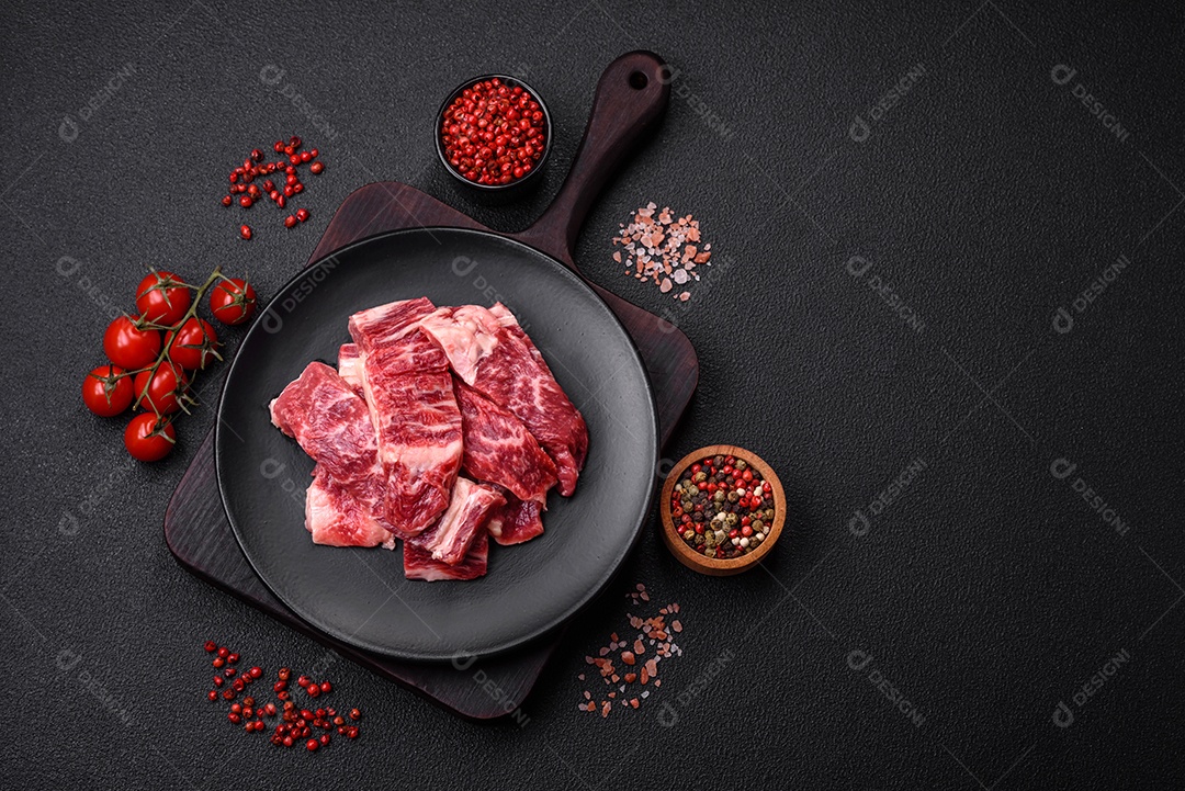 Bife fresco e suculento de carne crua com sal e especiarias sobre um fundo escuro de concreto