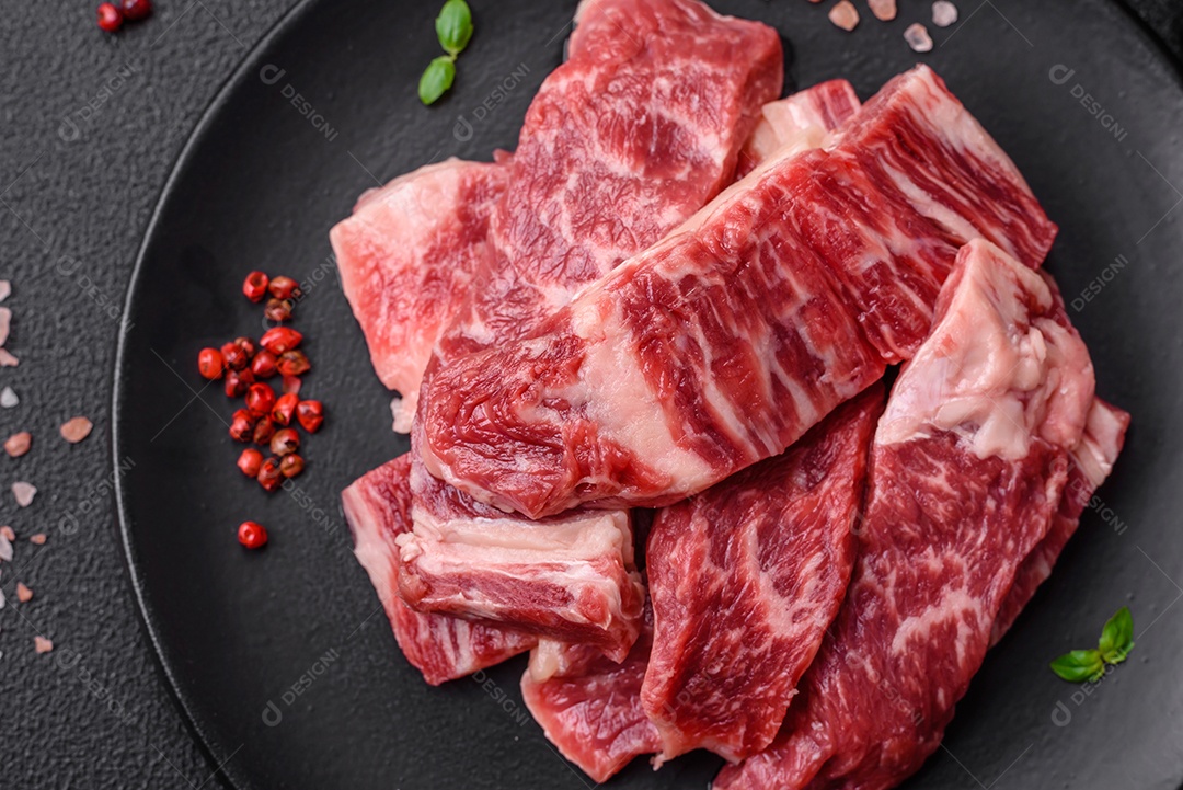Bife fresco e suculento de carne crua com sal e especiarias sobre um fundo escuro de concreto
