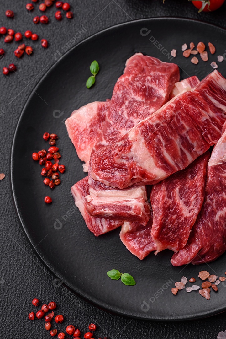 Bife fresco e suculento de carne crua com sal e especiarias sobre um fundo escuro de concreto
