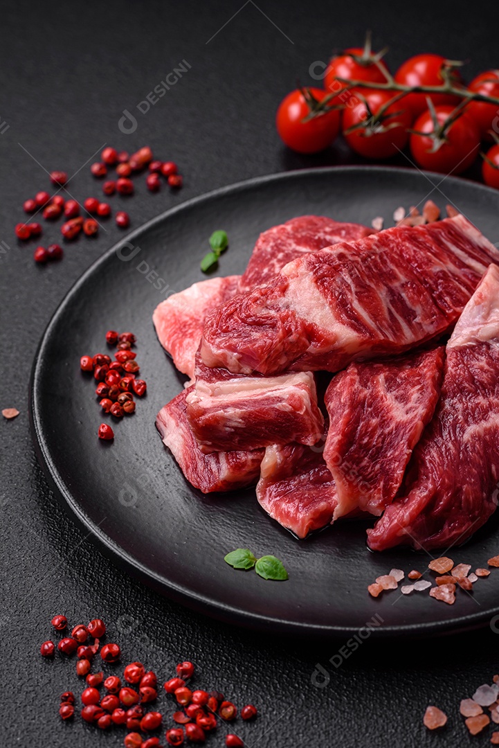 Bife fresco e suculento de carne crua com sal e especiarias sobre um fundo escuro de concreto