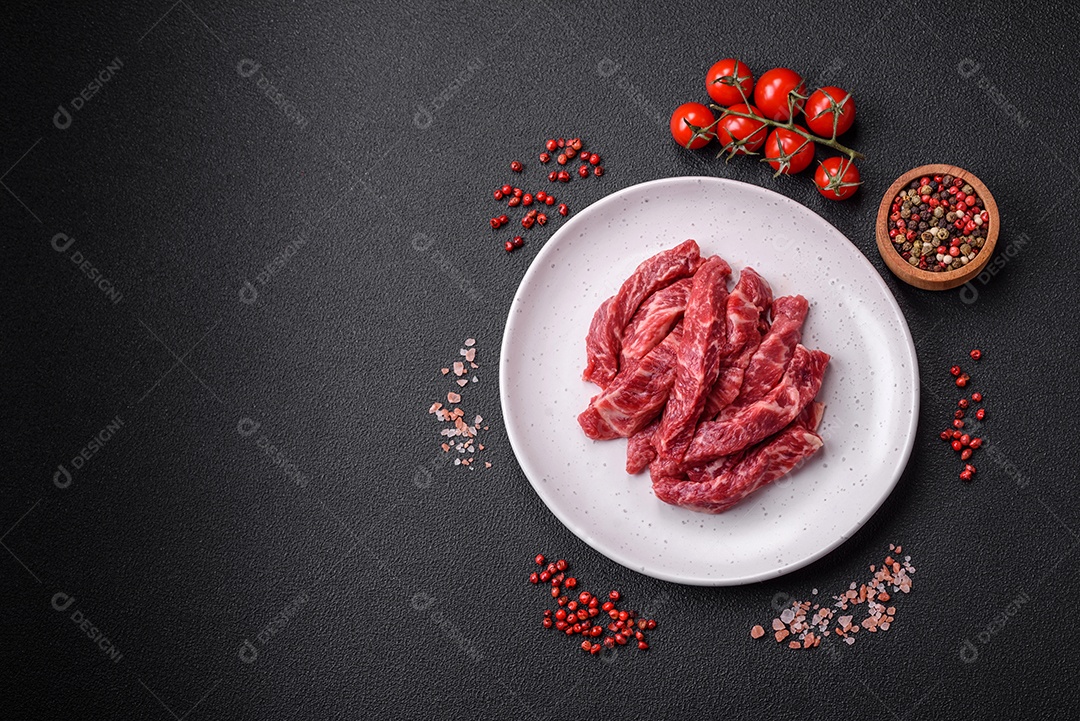 Carne de peru crua em forma de fatias com sal, especiarias e ervas sobre um fundo escuro de concreto