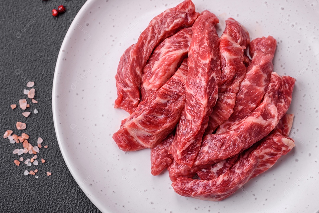 Carne de peru crua em forma de fatias com sal, especiarias e ervas sobre um fundo escuro de concreto