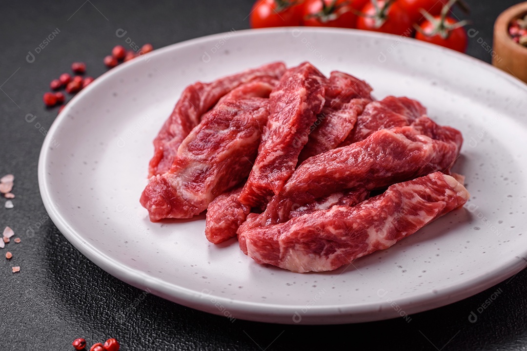 Carne de peru crua em forma de fatias com sal, especiarias e ervas sobre um fundo escuro de concreto