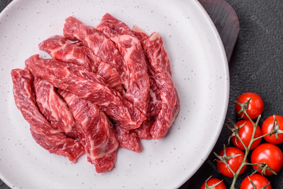 Carne de peru crua em forma de fatias com sal, especiarias e ervas sobre um fundo escuro de concreto