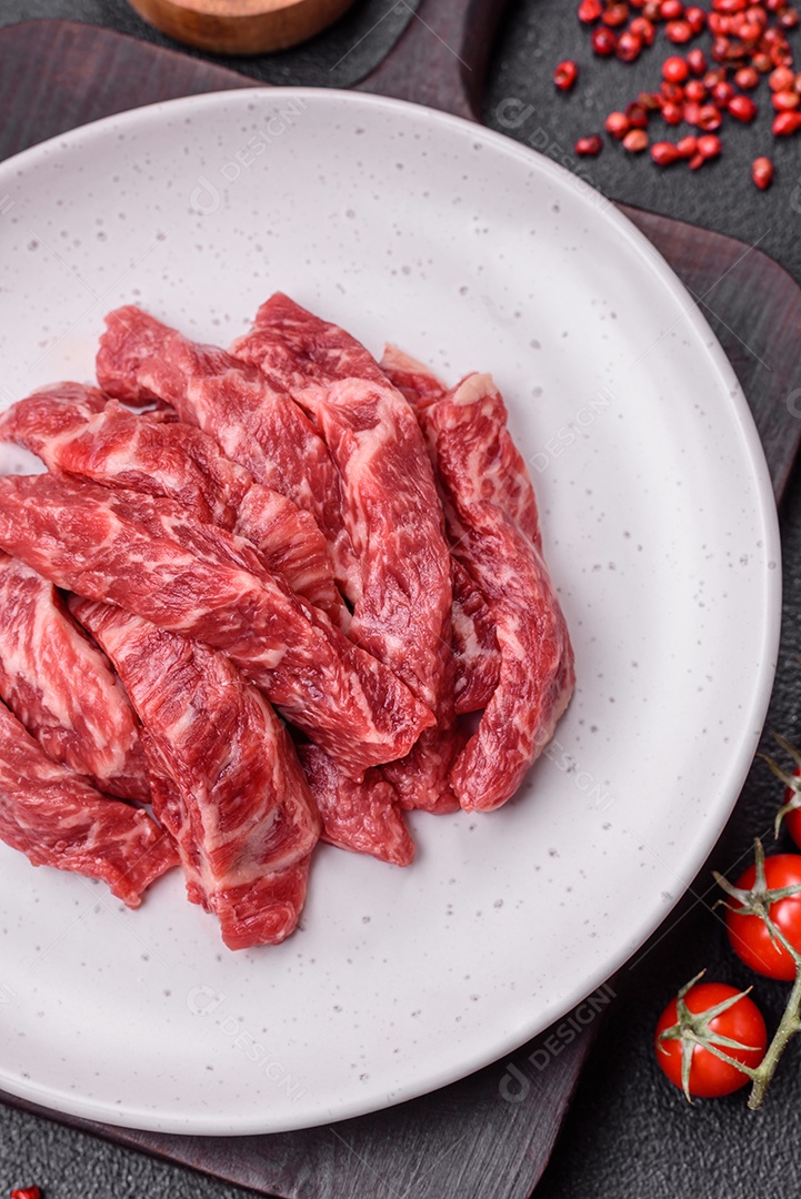 Carne de peru crua em forma de fatias com sal, especiarias e ervas sobre um fundo escuro de concreto