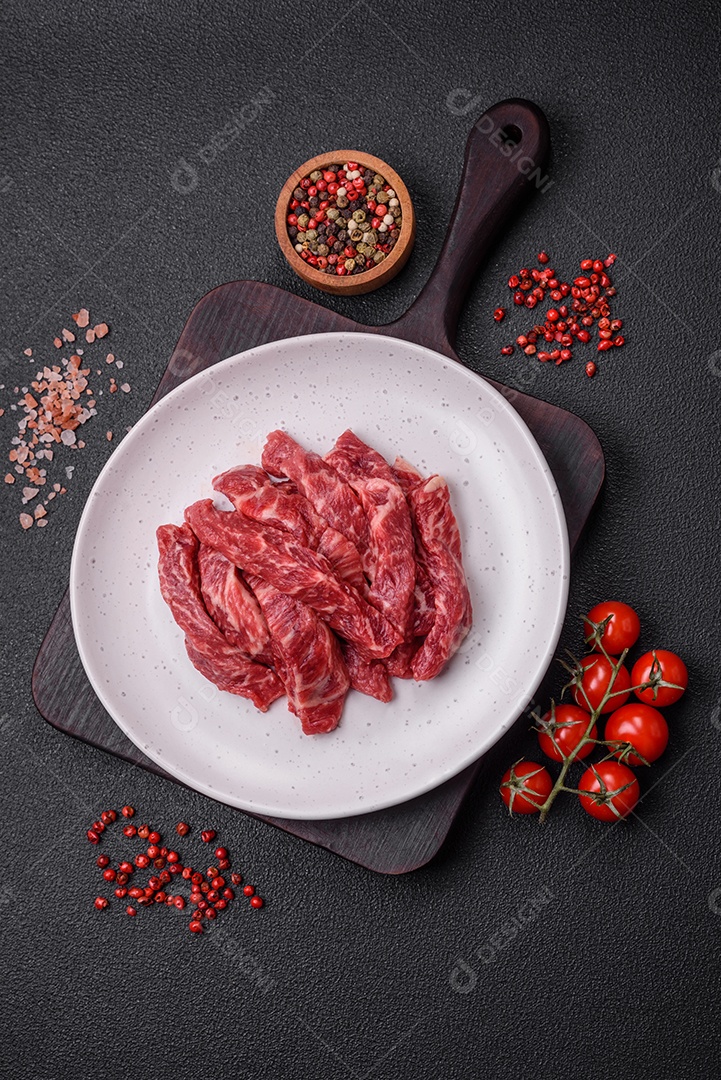 Carne de peru crua em forma de fatias com sal, especiarias e ervas sobre um fundo escuro de concreto