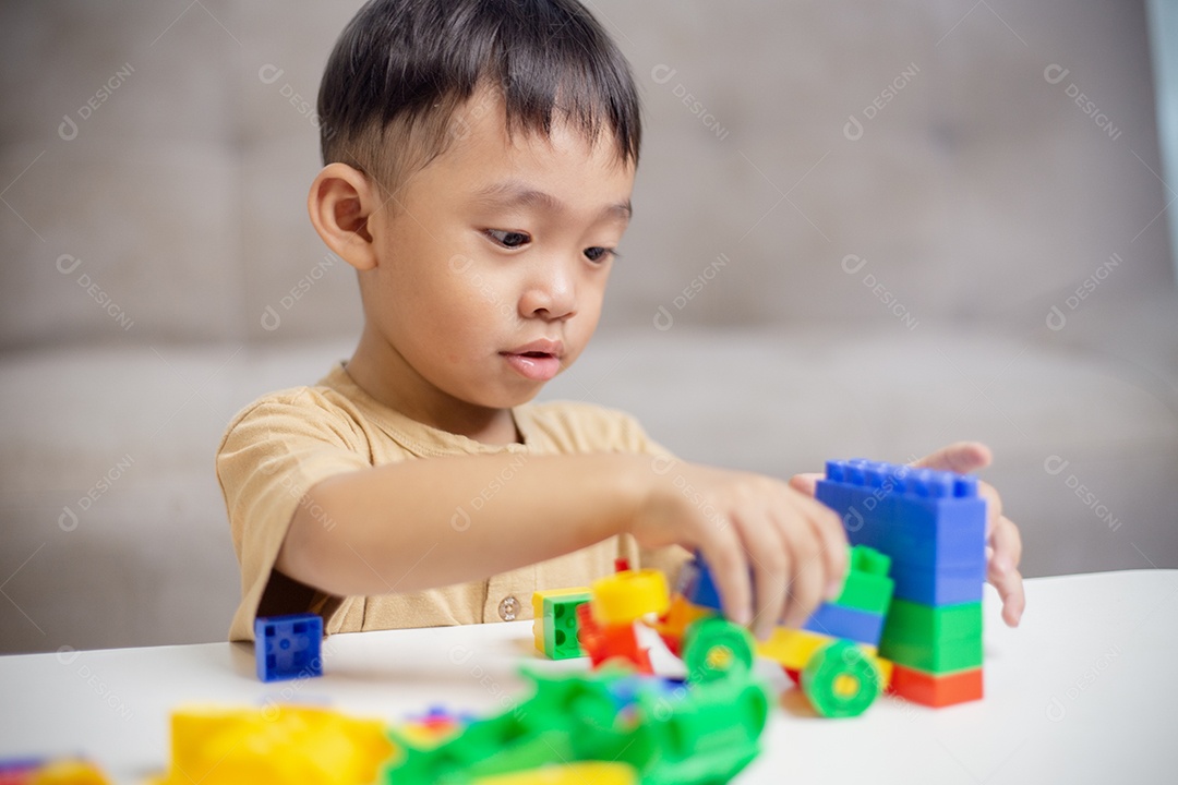 A criança brincando com blocos de brinquedos coloridos. Garotinho construindo o carro de brinquedos de bloco.
