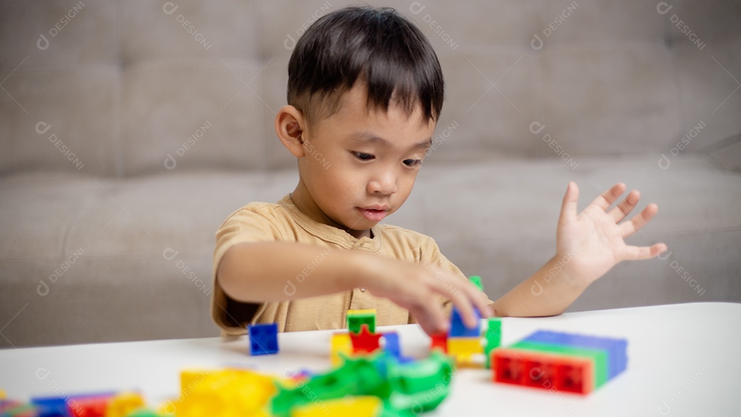 A criança brincando com blocos de brinquedos coloridos. Garotinho construindo o carro de brinquedos de bloco.