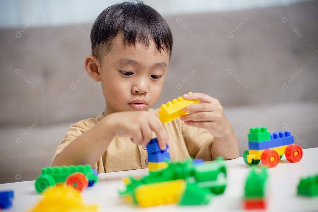 A criança brincando com blocos de brinquedos coloridos. Garotinho construindo o carro de brinquedos de bloco.