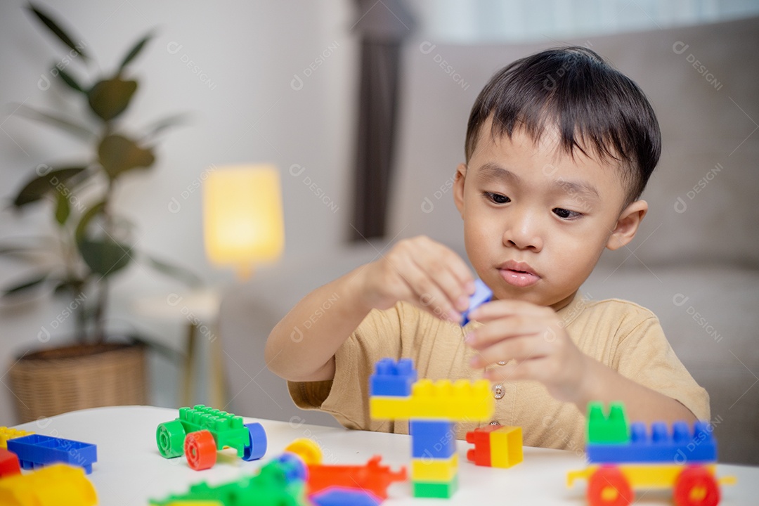 A criança brincando com blocos de brinquedos coloridos. Garotinho construindo o carro de brinquedos de bloco.