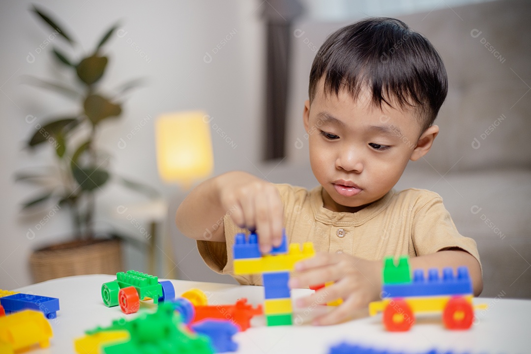 A criança brincando com blocos de brinquedos coloridos. Garotinho construindo o carro de brinquedos de bloco.