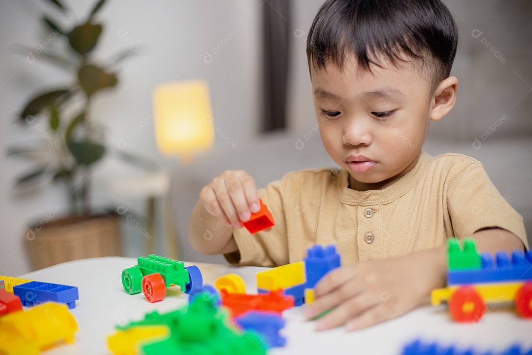 A criança brincando com blocos de brinquedos coloridos. Garotinho construindo o carro de brinquedos de bloco.