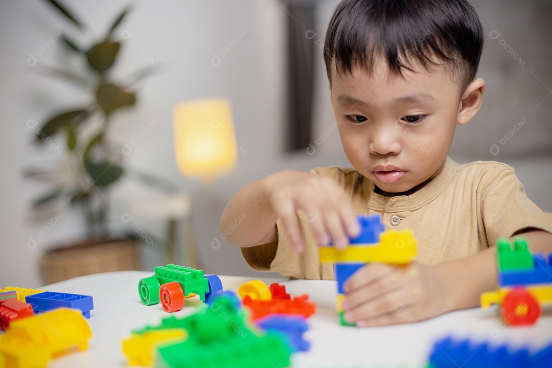 A criança brincando com blocos de brinquedos coloridos. Garotinho construindo o carro de brinquedos de bloco.