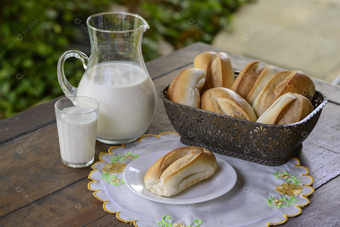 Pão em uma cesta e leite em uma jarra de vidro sobre uma mesa de madeira