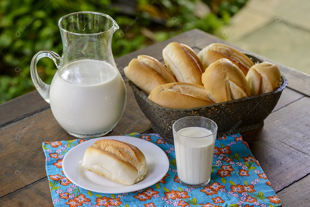 Pão em uma cesta e leite em uma jarra de vidro sobre uma mesa de madeira