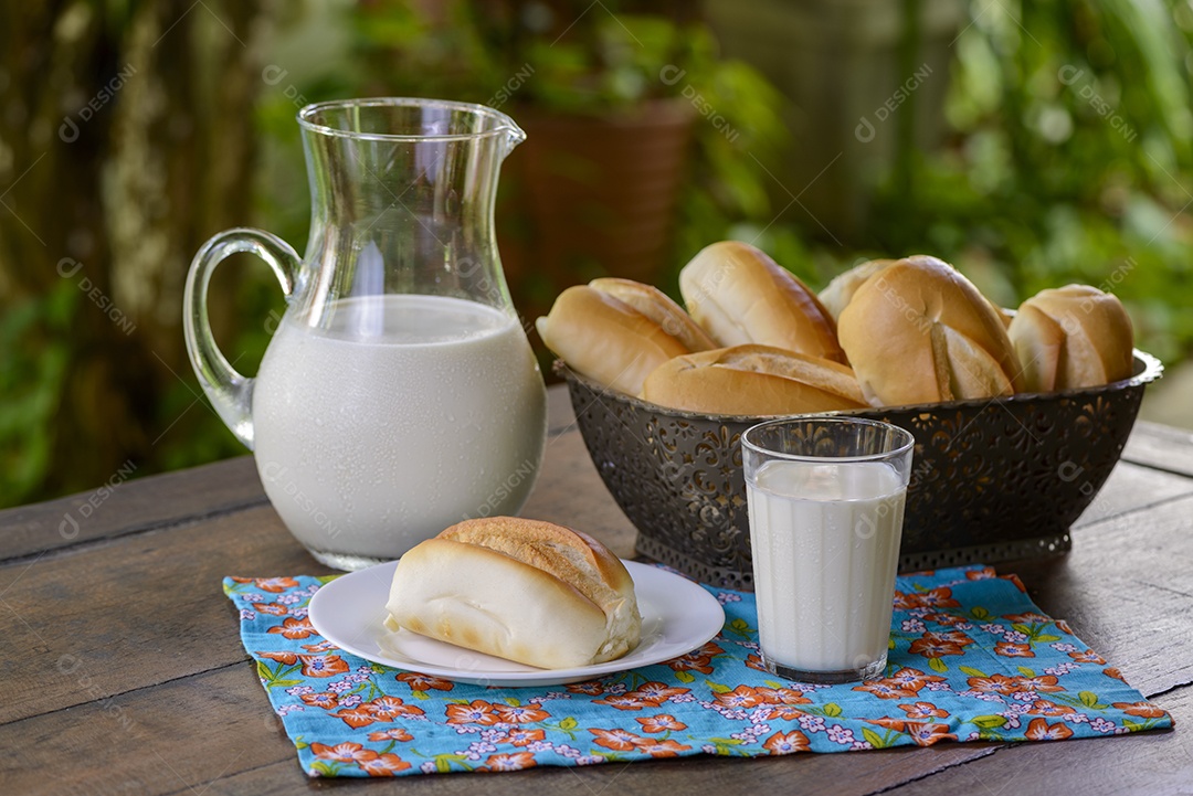 Pão em uma cesta e leite em uma jarra de vidro sobre uma mesa de madeira