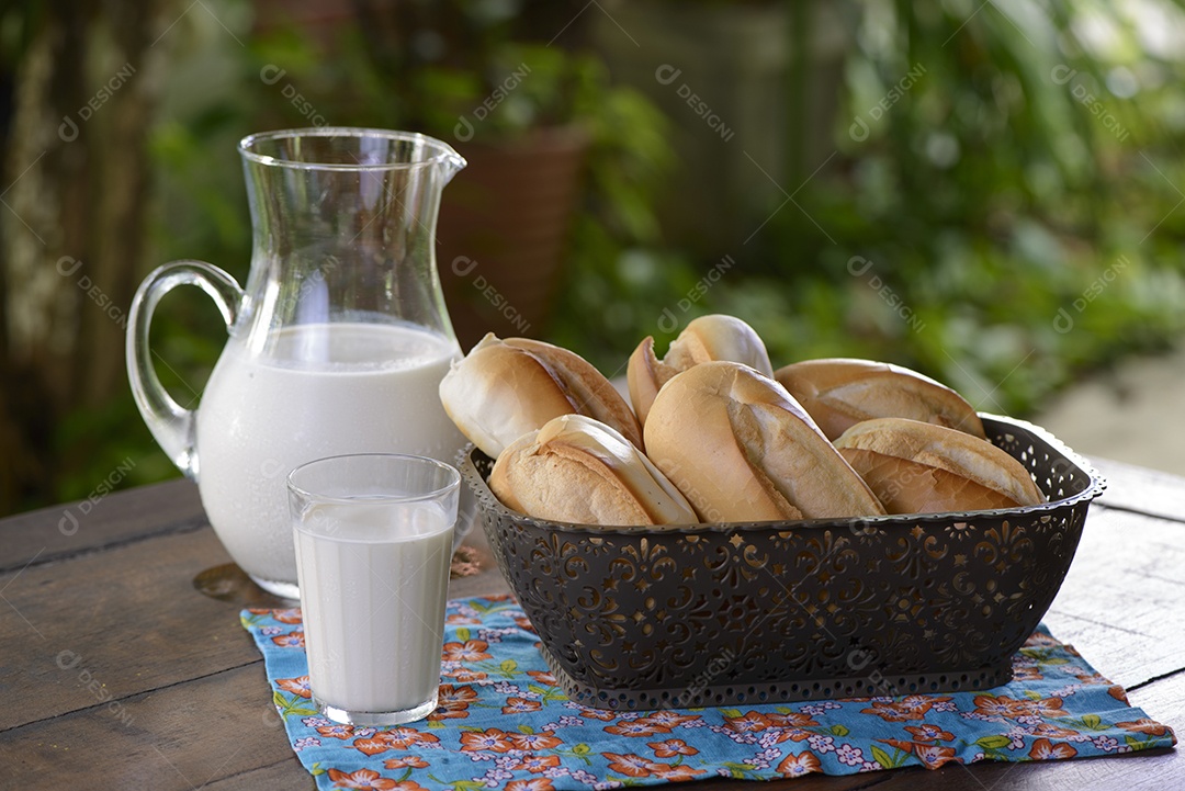 Pão em uma cesta e leite em uma jarra de vidro sobre uma mesa de madeira