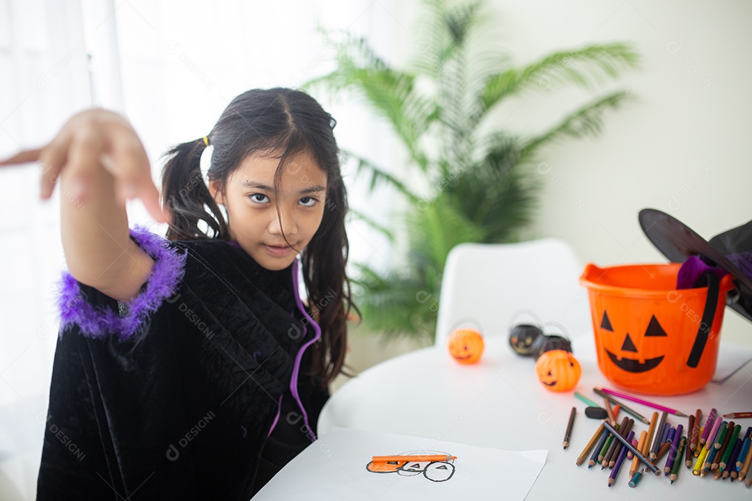Menina asiática feliz em uma fantasia de bruxa para o Halloween.