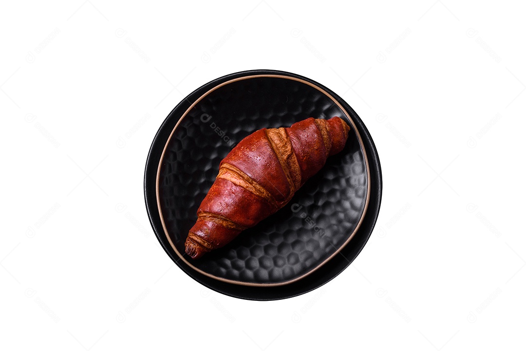 Delicioso croissant crocante com chocolate em uma placa de cerâmica preta sobre um fundo escuro de concreto