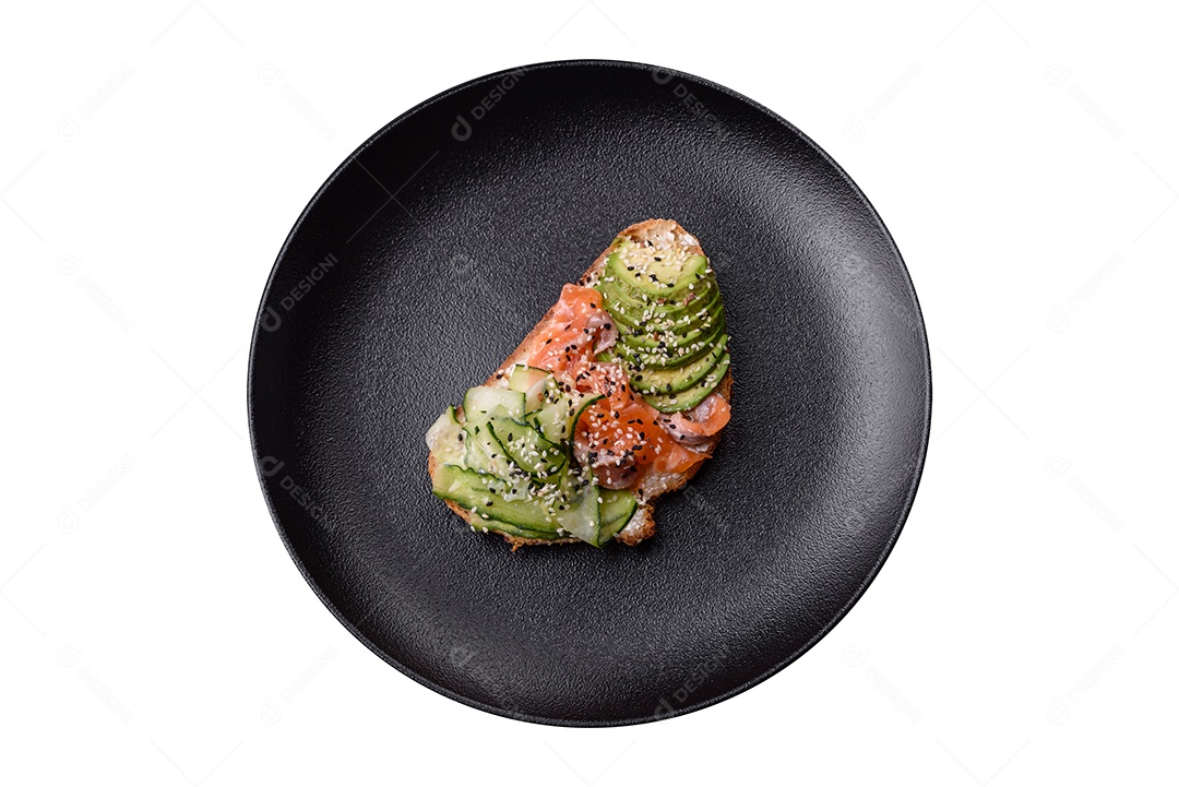 Sanduíche fresco e saboroso com salmão, abacate e sementes de gergelim e linho sobre um fundo escuro de concreto