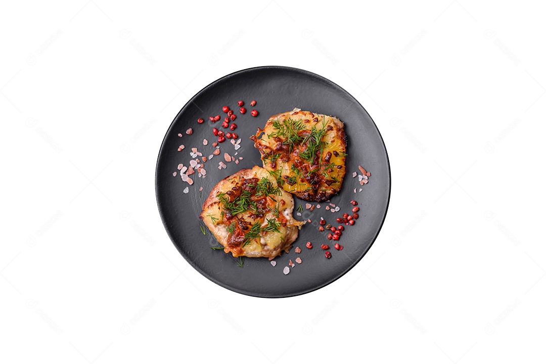 Carne assada no forno com abacaxi, tomate, queijo, especiarias e ervas em uma placa de cerâmica preta sobre fundo escuro de concreto