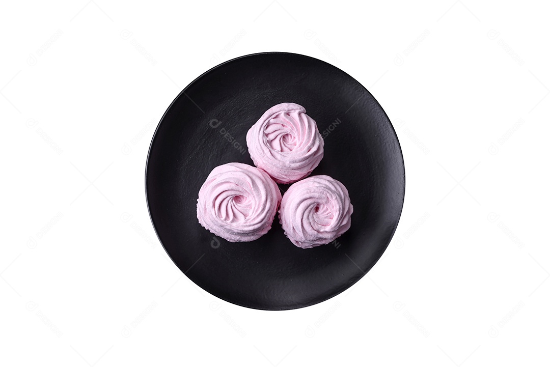 Deliciosos marshmallows arejados naturais e frescos em uma placa de cerâmica preta sobre um fundo escuro de concreto