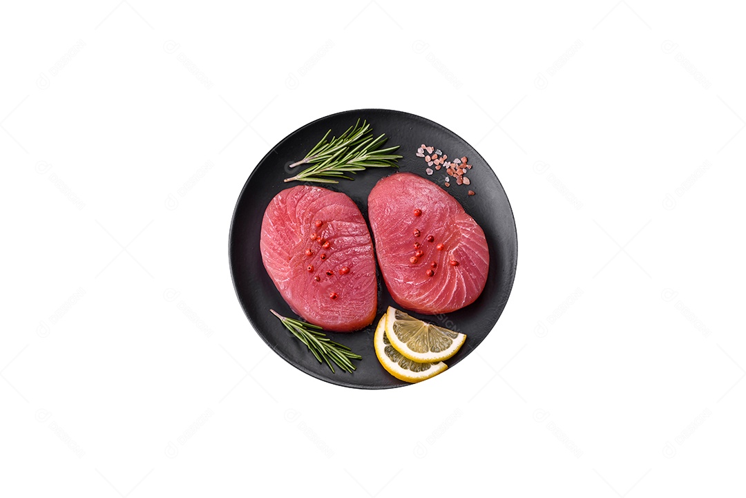 Duas fatias frescas de filé de atum cru com especiarias e ervas sobre um fundo escuro de concreto