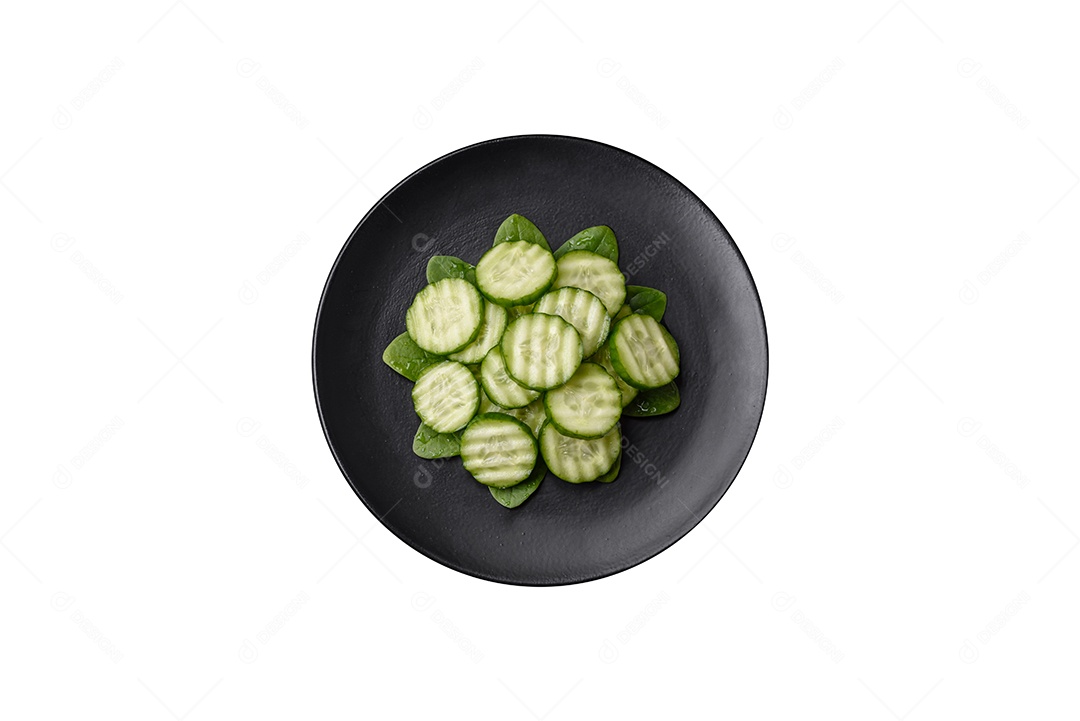 Delicioso pepino cru saudável cortado em uma placa de cerâmica preta sobre um fundo escuro de concreto