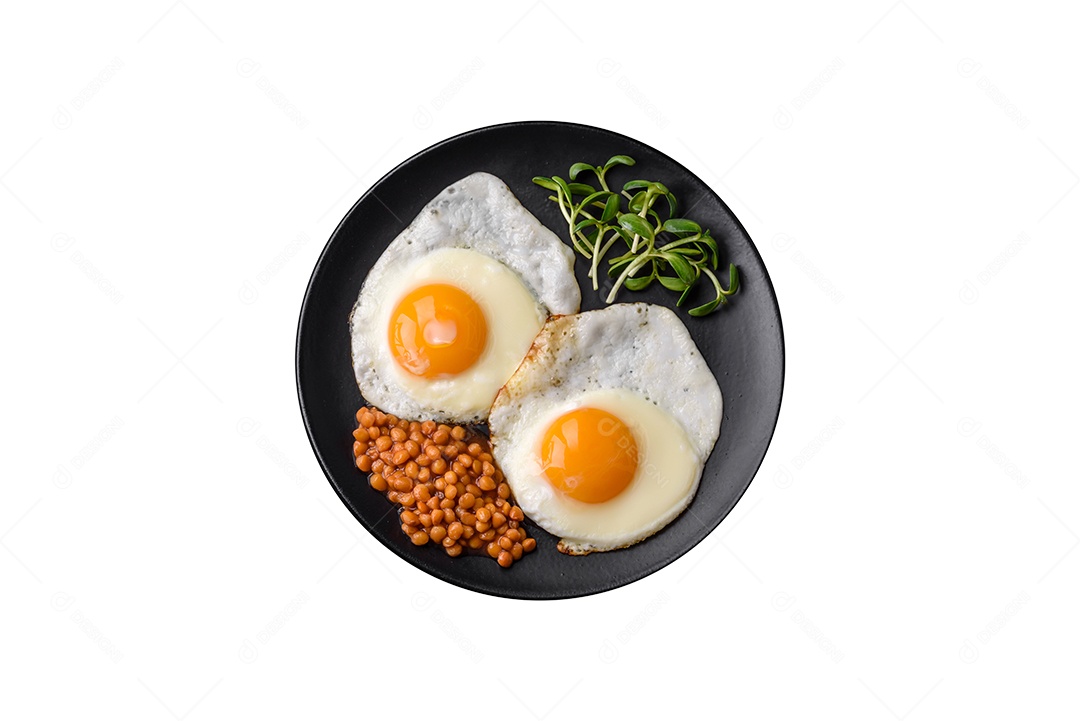 Delicioso café da manhã inglês nutritivo com ovos fritos, tomates e abacate com especiarias e ervas em um fundo escuro de concreto