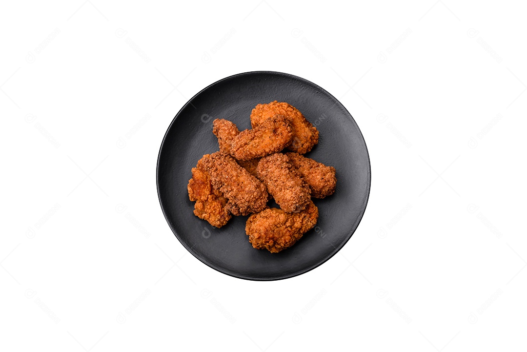 Deliciosos nuggets de frango crocantes com sal e especiarias em um fundo escuro de concreto.