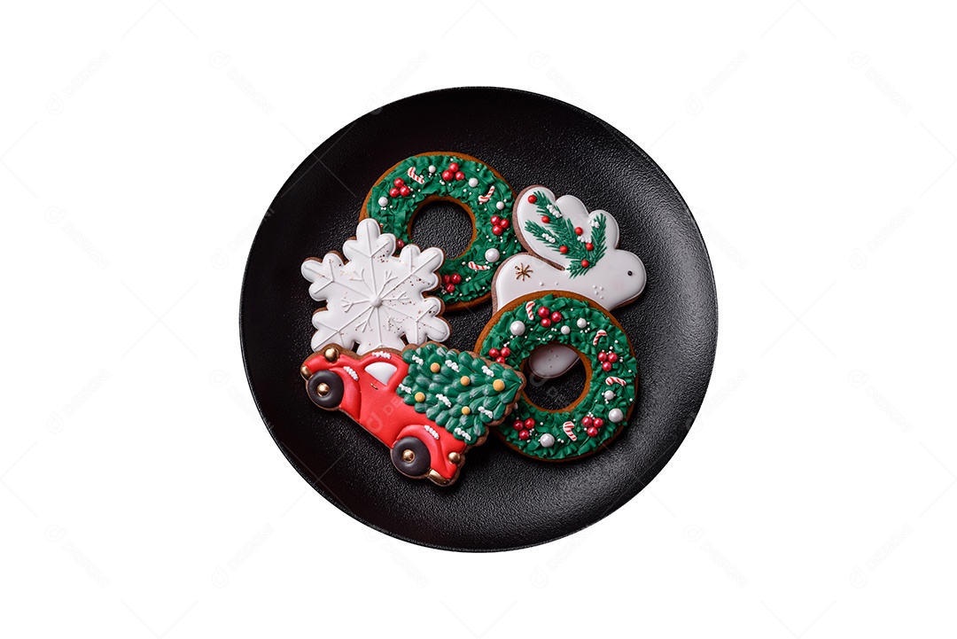 Lindos biscoitos de gengibre caseiros coloridos de Natal ou Ano Novo em uma placa cerâmica sobre um fundo escuro de concreto