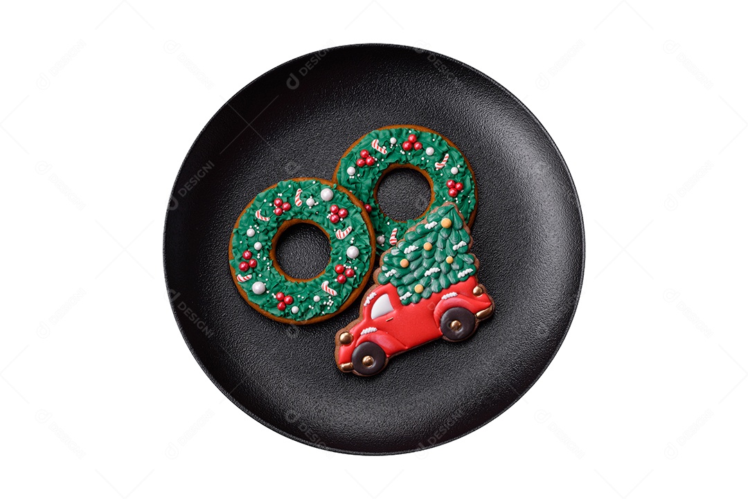 Lindos biscoitos de gengibre caseiros coloridos de Natal ou Ano Novo em uma placa cerâmica sobre um fundo escuro de concreto