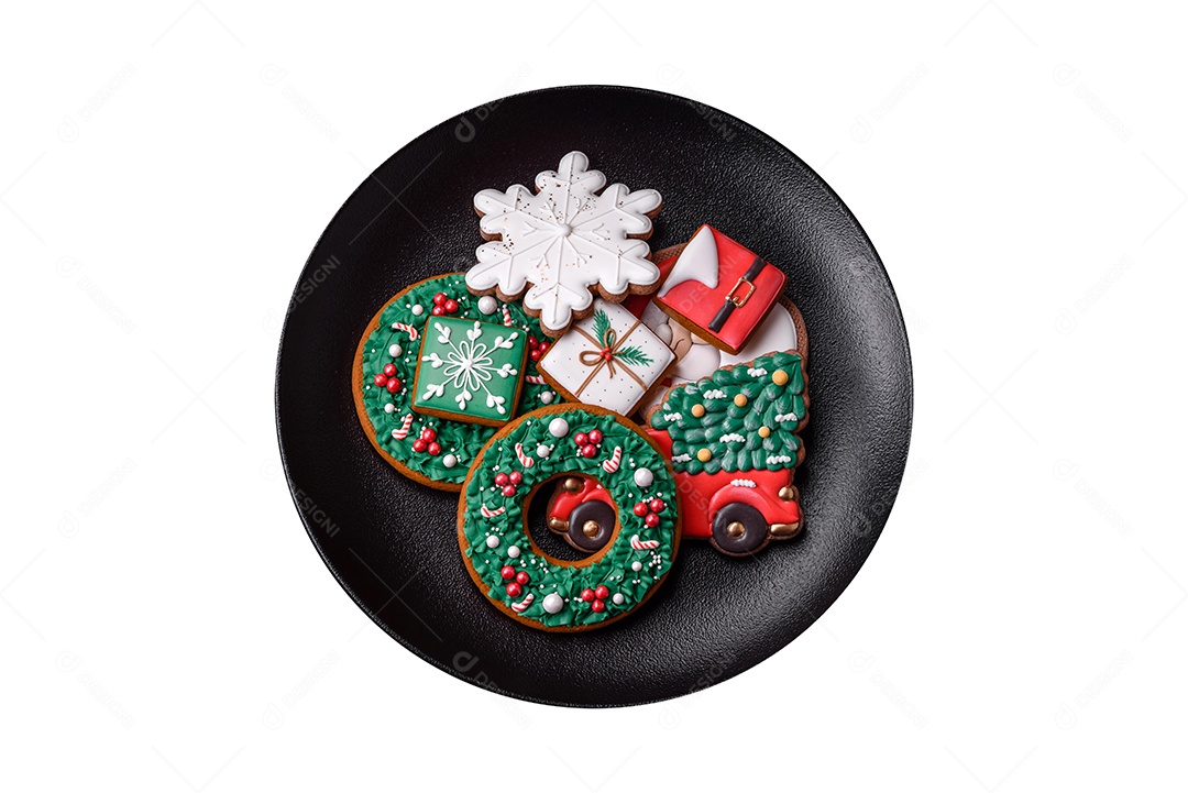 Deliciosos biscoitos de gengibre frescos e coloridos de Natal ou Ano Novo em uma placa de cerâmica sobre um fundo escuro de concreto